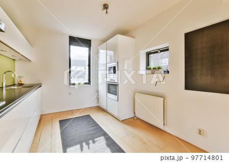 an empty kitchen and dining area in a house with white walls, hardwood flooring and black countertops on the wall an empty kitchen and dining area in a house with white walls, hardwood flooring and black countertops on the wall 97714801
