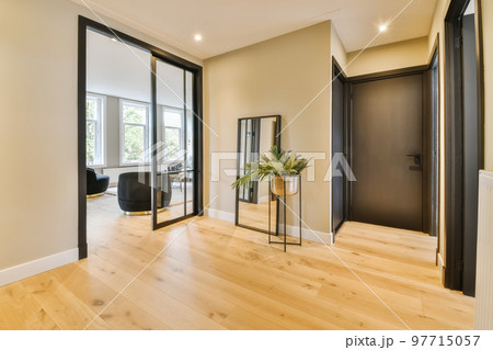 a living room with wood flooring and black trim on the doors, in front of an open door that leads to another room a living room with wood flooring and black trim on the doors, in front of an open door that leads to another room 97715057