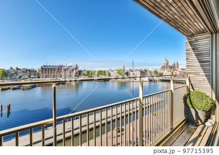 a balcony with a view of the water and buildings in the distance, taken from an apartment window looking out onto the canal 97715395