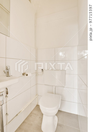 a bathroom with white tiles on the walls, and a toilet in the corner next to the sink is visible a bathroom with white tiles on the walls, and a toilet in the corner next to the sink is visible 97715397