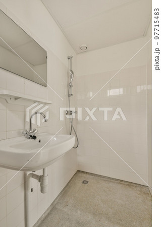 Interior of narrow restroom with sink and flush toilet Interior of narrow restroom with sink and flush toilet 97715483