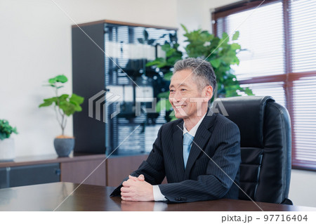 笑顔で椅子に座る経営者の男性 97716404