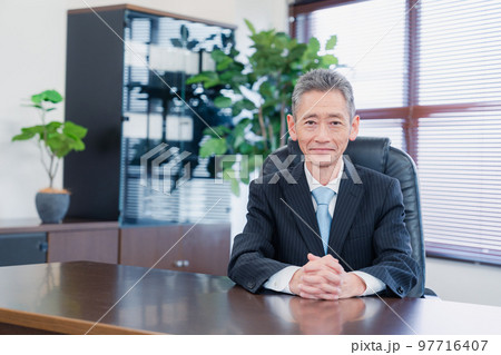 笑顔で椅子に座る経営者の男性 97716407