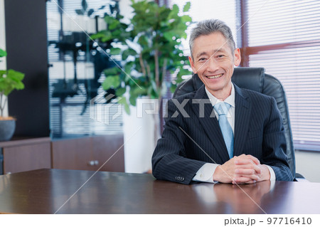 笑顔で椅子に座る経営者の男性 97716410