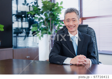 笑顔で椅子に座る経営者の男性 97716411