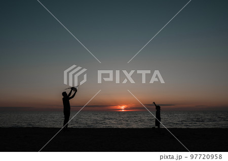 happy family father and child daughter run with kite in the meadow. silhouettes on the background of the sea sunset. High quality photo. 97720958
