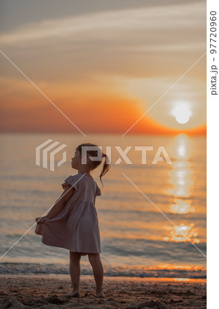 girl playing on the beach at sunset. Family holiday. High quality photo. 97720960