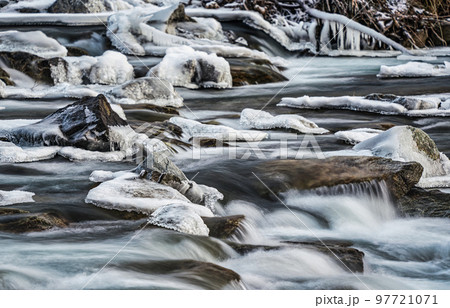 Winter river flowing over snow and ice covered stones, closeup detail, long exposure photo Winter river flowing over snow and ice covered stones, closeup detail, long exposure photo 97721071
