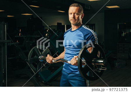 Fit elderly man lifting barbell in a gym Fit elderly man lifting barbell in a gym 97721375