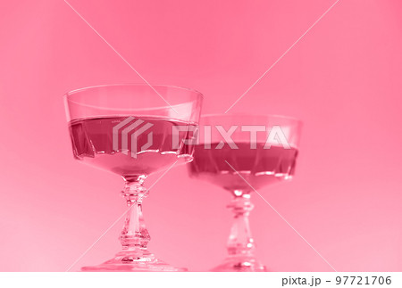 Two crystal glasses of sparkling wine or champagne. Toned image in trendy magenta color of year 2023. Minimal creative composition with copy space. 97721706