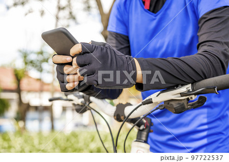 Woman using smartphone while sitting on her bicycle Woman using smartphone while sitting on her bicycle 97722537