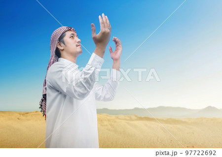 Muslim man with keffiyeh and agal raised hands and praying 97722692