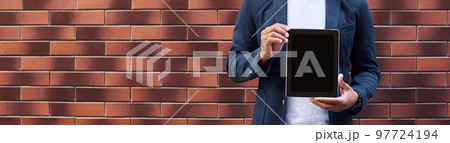 Promotion. Young guy standing on wall showing screen of digital tablet looking camera smiling happy 97724194