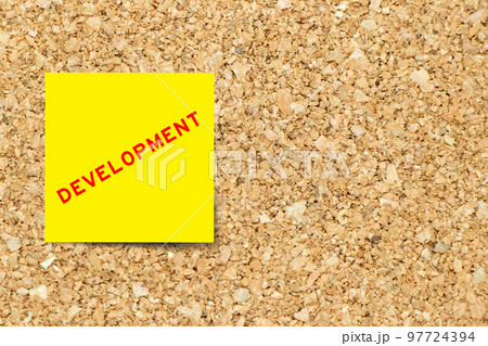 Yellow note paper with word development on cork board background with copy space 97724394