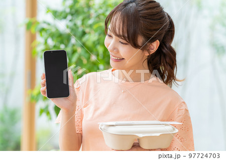 お弁当とスマホを持つ若い女性 97724703