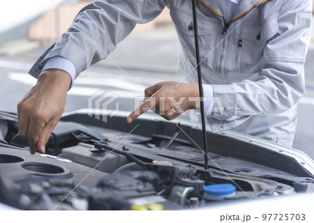 エンジンオイルのレベルゲージを確認する男性自動車整備士の手 97725703