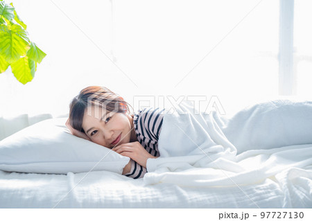 ベッドで快眠で目を覚ます笑顔の女性 97727130