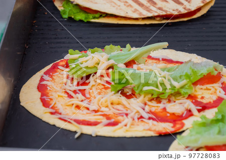 Preparing fresh quesadilla on black grill at summer local food market 97728083