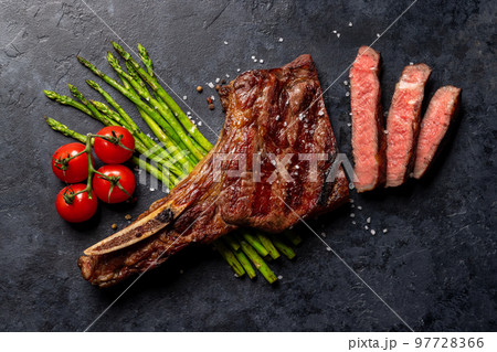 Medium rare grilled Tomahawk beef steak with asparagus Medium rare grilled Tomahawk beef steak with asparagus 97728366