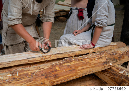 Man carpenter using drawknife to shape and smooth wood board Man carpenter using drawknife to shape and smooth wood board 97728660