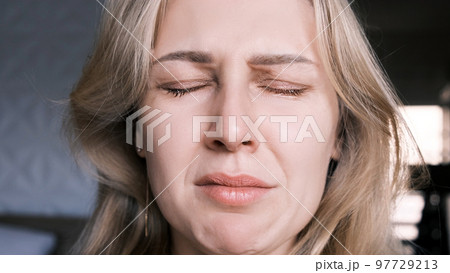 Portrait of crying grieving woman of 30 years. Grimace of sadness with tears in her eyes and crooked chin of blonde woman looking at camera. Emotional swing, unstable psyche, mental problems 97729213