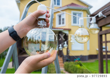 Incandescent lamp in hands close-up. Backyard cleaning Incandescent lamp in hands close-up. Backyard cleaning 97729893