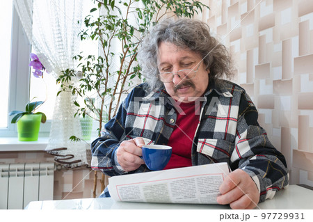 A portrait of an old man reading a newspaper with a cup of coffee. A notion of people and lifestyle A portrait of an old man reading a newspaper with a cup of coffee. A notion of people and lifestyle 97729931