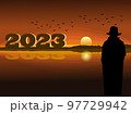 silhouette of a man standing looking at the numbers 2023 With the sea and the sunset in the background 97729942