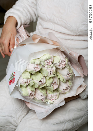 Marshmallow bouquet. Zephyr tulips. Natural homemade marshmallow. Packed in paper in the form of a bouquet. In the hands of a woman. Close-up. Marshmallow bouquet. Zephyr tulips. Natural homemade marshmallow. Packed in paper in the form of a bouquet. In the hands of a woman. Close-up. 97730298