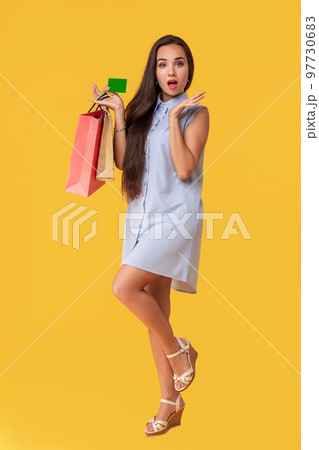 Charming pretty attractive sexy girl showing credit card and holding many colorful packages in hand, it is comfortable to use bank card for shopping, standing over yellow background Charming pretty attractive sexy girl showing credit card and holding many colorful packages in hand, it is comfortable to use bank card for shopping, standing over yellow background 97730683