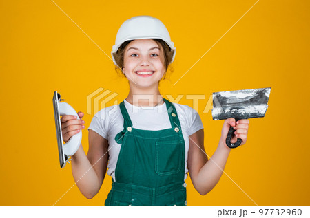teen girl plasterer in protective helmet use spatula, plastering tool 97732960