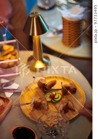 Wooden round plate with delicious snacks on cafe table 97733495