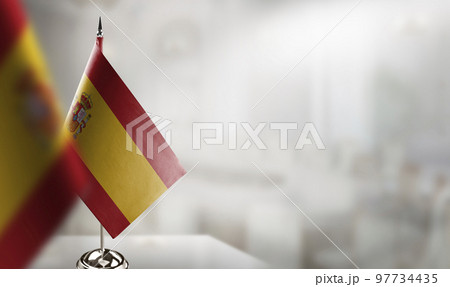 Small flags of the Spain on an abstract blurry background Small flags of the Spain on an abstract blurry background 97734435