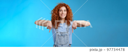 Excited happy smiling caring redhead curly-haired girlfriend thrilled awaiting summer holiday trip pointing down index finger upbeat mood show favorite store buy best prices, blue background Excited happy smiling caring redhead curly-haired girlfriend thrilled awaiting summer holiday trip pointing down index finger upbeat mood show favorite store buy best prices, blue background 97734478