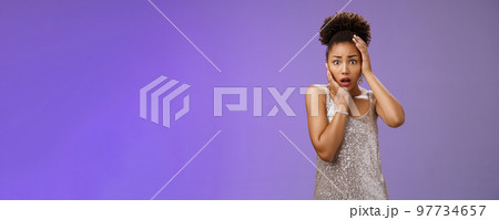 Shocked afraid timid insecure african-american woman in silver trendy dress panic widen eyes frightened look camera touch head terrified anxiously staring gasping speechless shook, blue background 97734657