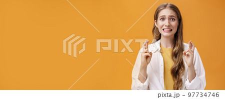 Girl hopes she did well on exam clenching teeth looking worried and concerned, crossing fingers for good luck praying making wish for dream come true waiting with expactation of miracle 97734746