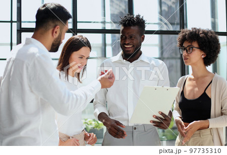 Employees working at computer together, discussing content Employees working at computer together, discussing content 97735310