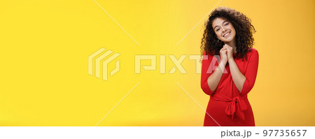 So sweet love you. Portrait of tender and silly cute curly-haired young woman in red dress tilting head holding hands together near face and smiling touched during heartwarming moment of confession So sweet love you. Portrait of tender and silly cute curly-haired young woman in red dress tilting head holding hands together near face and smiling touched during heartwarming moment of confession 97735657