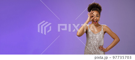 Good-looking charismatic enthusiastic flirty african-american woman in silver evening dress hold hand waist joyfully smiling open mouth impressed look through okay ok gesture amused 97735703