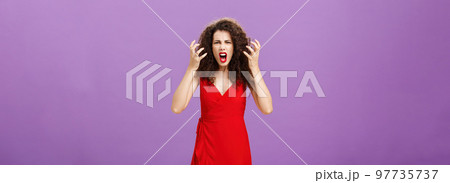 Woman getting annoyed and pissed employees spoiling her perfomance. Portrait of outraged furious female musician in red evening dress raising clenched fists grimacing and yelling angry Woman getting annoyed and pissed employees spoiling her perfomance. Portrait of outraged furious female musician in red evening dress raising clenched fists grimacing and yelling angry 97735737