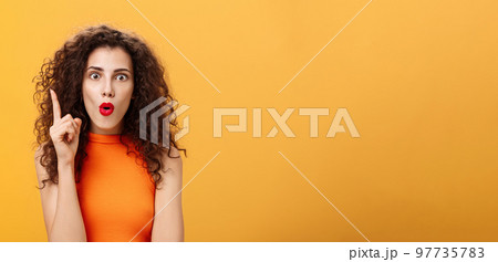 I got excellent plan. Enthusiastic emotive and excited female with curly hairstyle in orange cropped top raising index finger in eureka gesture folding lips popping eyes adding amazing suggestion I got excellent plan. Enthusiastic emotive and excited female with curly hairstyle in orange cropped top raising index finger in eureka gesture folding lips popping eyes adding amazing suggestion 97735783