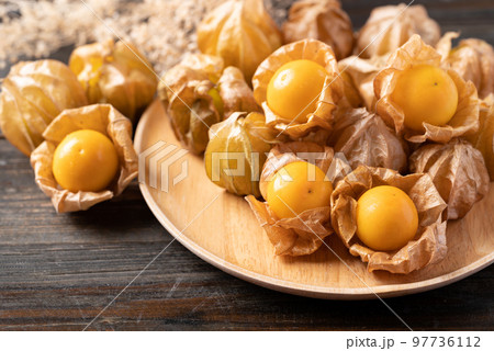 Cape gooseberry or golden berry (Physalis peruviana) on wooden plate 97736112