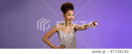 Impressed fascinated cute african-american woman excited pointing index finger sideways thrilled enjoying incredible exhibition standing excited blue background, glancing amused Impressed fascinated cute african-american woman excited pointing index finger sideways thrilled enjoying incredible exhibition standing excited blue background, glancing amused 97736140