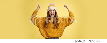 Relieved attractive fashionable university female student yelling proudly raise clenched fists victory cheer gesture celebrating win successful achievement accomplishment goal, yellow background 97736266