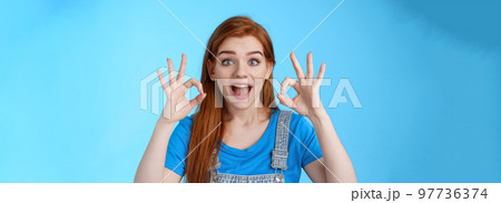 Excellent choice. Redhead female friend approve awesome idea, support accept good purshace, show okay ok confirmation gesture, smiling judging, give positive feedback, stand satisfied blue background 97736374