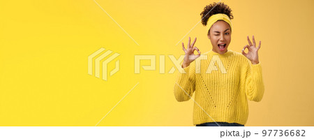 Okay I got it. Cute reliable truthful african-american girlfriend assuring friend secret safe winking devious hinting work done okay show ok fine perfect gesture no worry about, yellow background 97736682