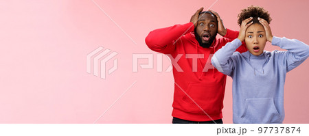 Shocked worried african american couple man woman holding hands head panicking widen eyes stunned receive bad concerning news feel troubled nervous, standing pink background anxious Shocked worried african american couple man woman holding hands head panicking widen eyes stunned receive bad concerning news feel troubled nervous, standing pink background anxious 97737874