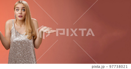 Unsure clueless awkward attractive blond european woman in silver glamour dress shrugging hands sideways widen eyes raise eyebrows unaware no idea what happening, standing questioned confused 97738021