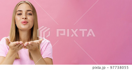 Spreading love to world. Portrait of charming sensual and tender romantic girlfriend holding palms over chest folding lips raising head and sending air kiss at camera with passion and romance 97738055