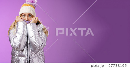 Afraid shocked young charming sister pulling jacket face cover hiding frightened scared terrifying stories snowman walking mountains widen eyes concerned look camera fear, standing purple background 97738196